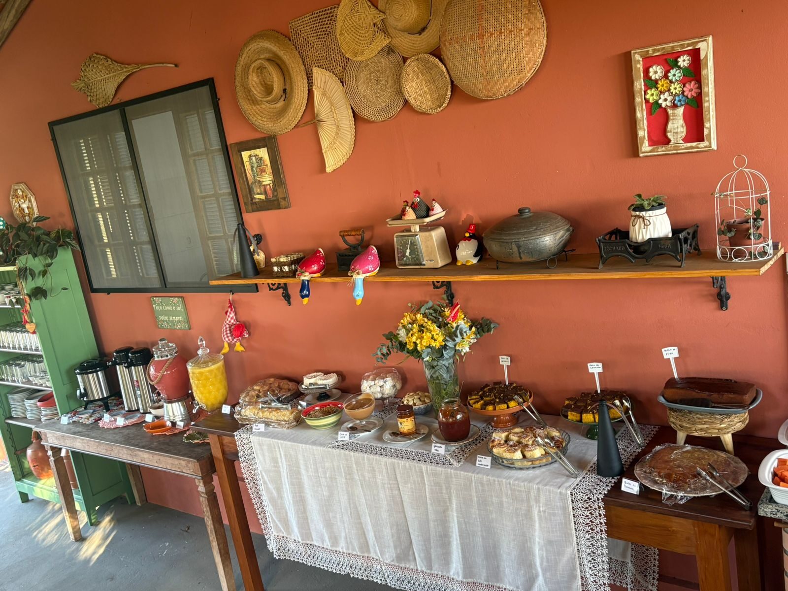 Buffet do café colonial com bolos, sucos, doces e decoração rústica