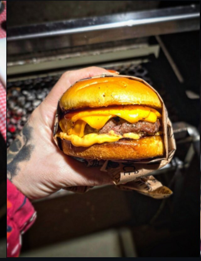 Cheeseburguer artesanal do Rancho Vovó Lulu na mão, com queijo derretido