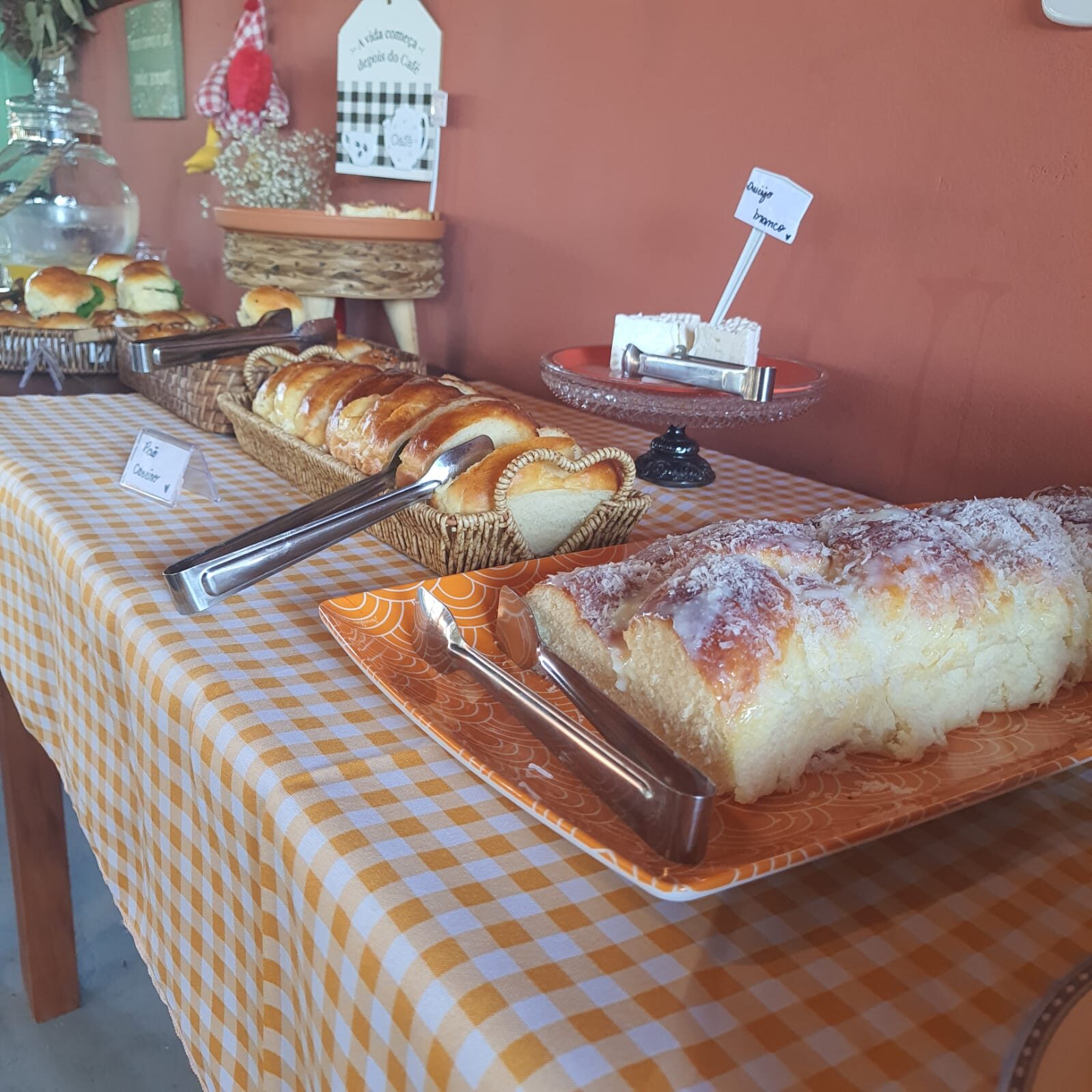 Mesa do café com pães caseiros, bolo e toalha xadrez