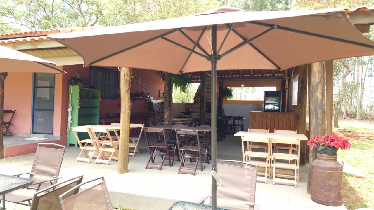 Pátio coberto com mesas e guarda-sol para eventos